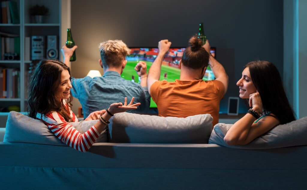Girls talking while men are watching soccer on TV